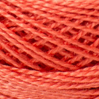 A close-up of bright coral pink thread or yarn wound into a skein, filling the entire frame.